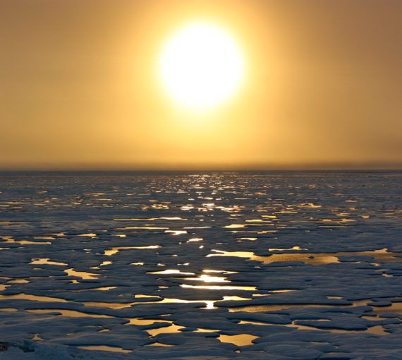 The sun sets over melting ice in the Arctic.