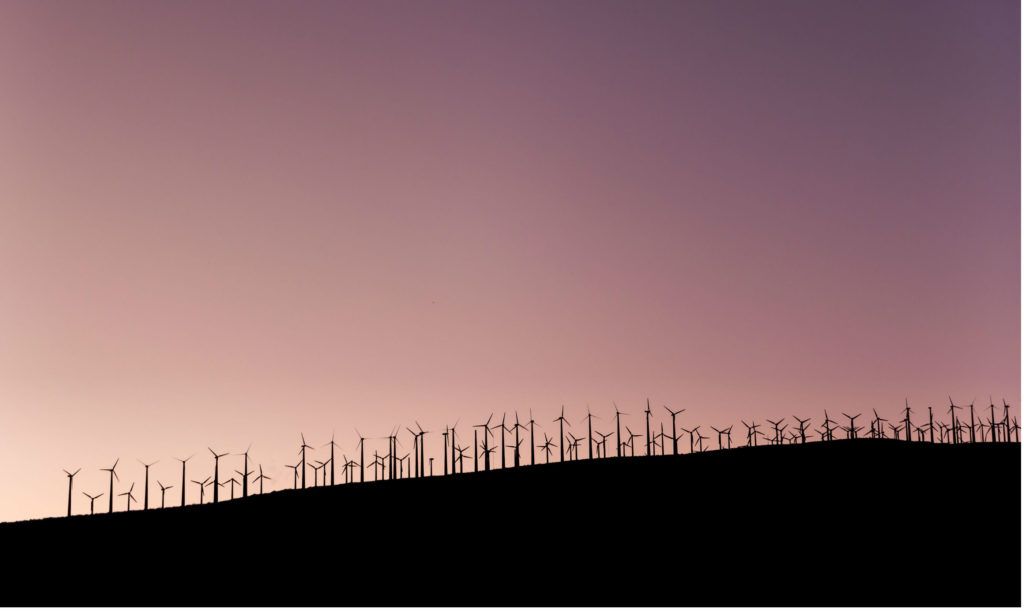 A picture of a wind farm on the horizon at dusk