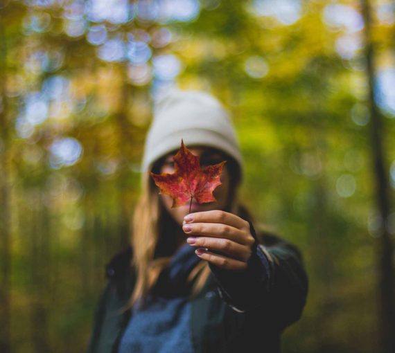 Woman in forest holding maple leaf