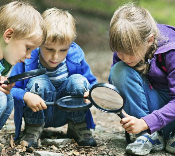 Connecting youth with nature - three children outside with magnifying glasses