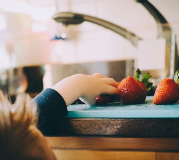 Child reaching for a washed strawberry