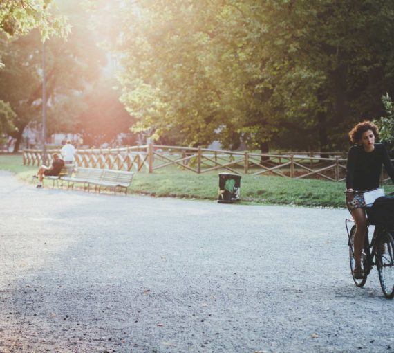 A woman rides her bicycle through a park