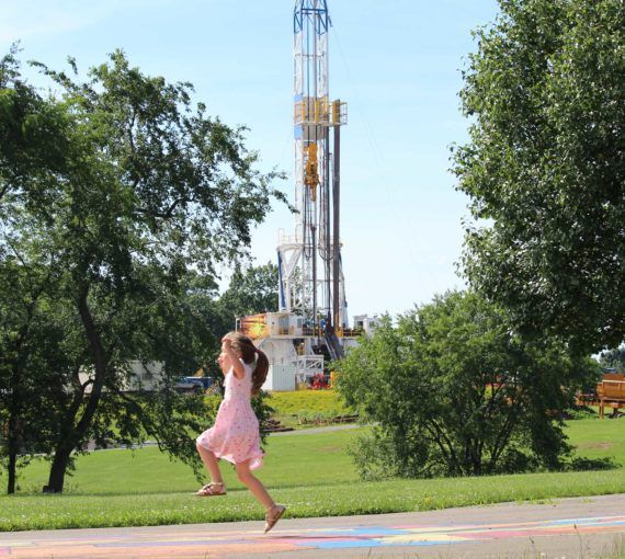 Girl playing near an oil well pad