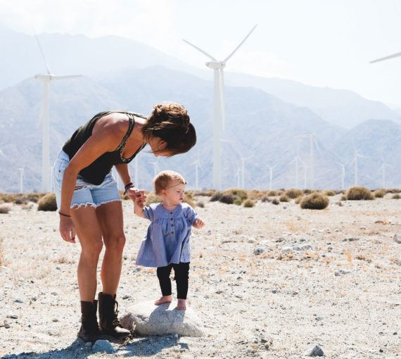 Young woman and toddler with wind turbines in the distance