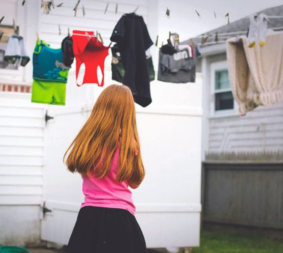 Girl in yard with laundry hanging from a clothesline