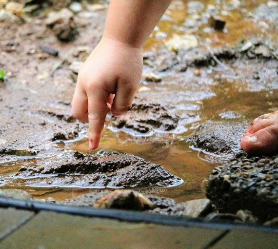 Child's hand playing in the mud