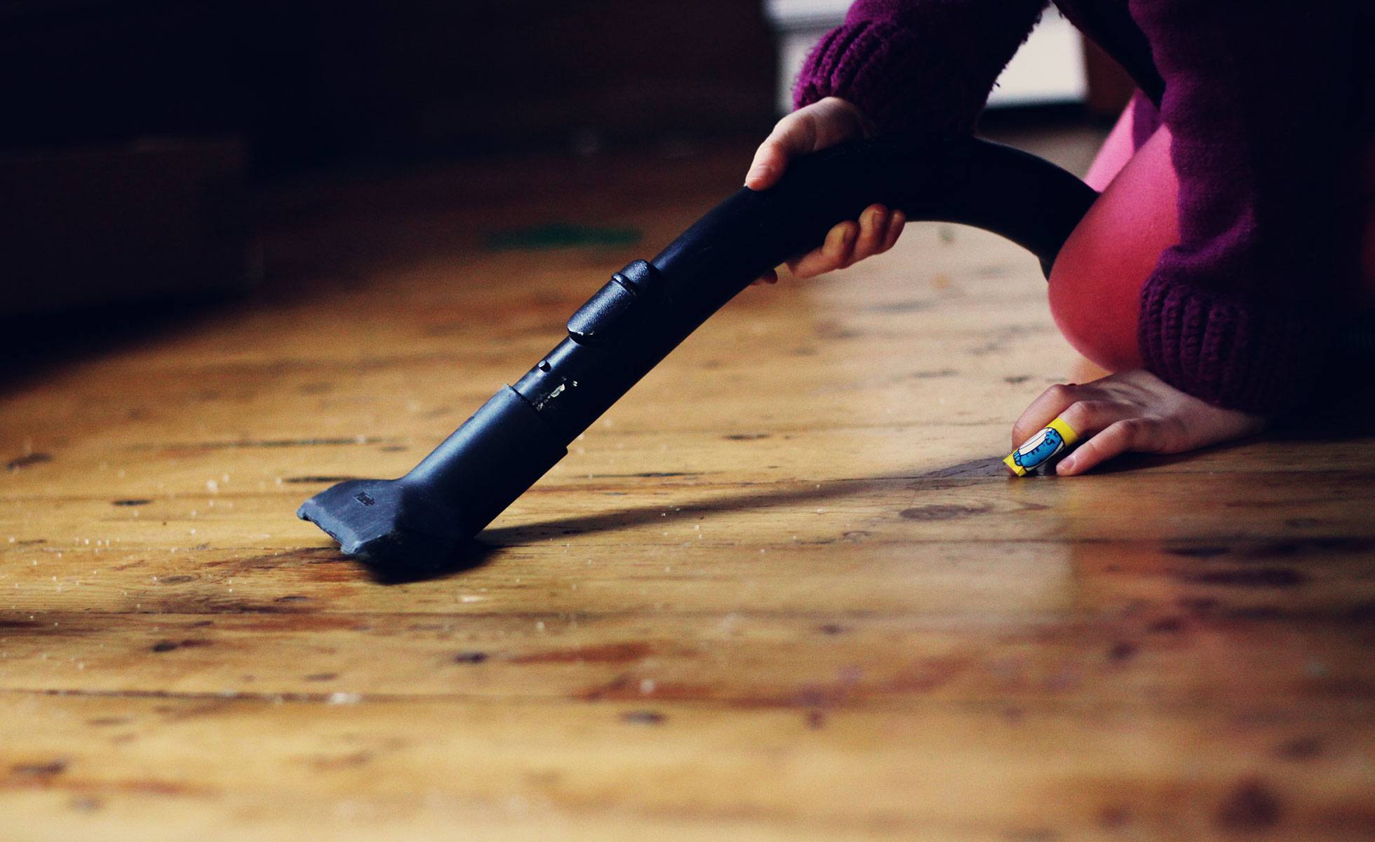 Child vacuuming dust off the floor