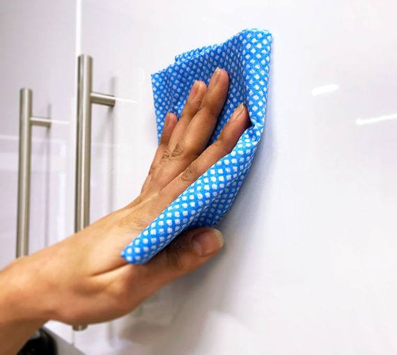 Hand wiping cabinet doors with a damp cloth
