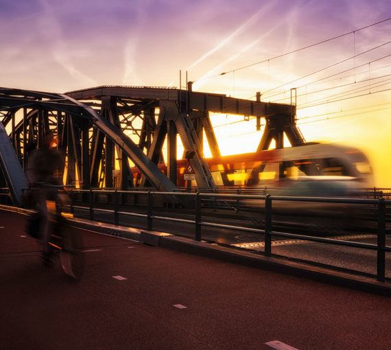 Cyclist and public transit commuter train share a bridge