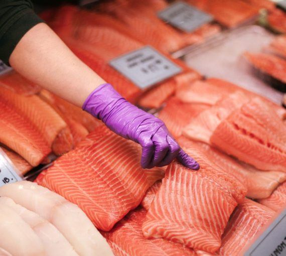 Person pointing at raw salmon at a seafood market