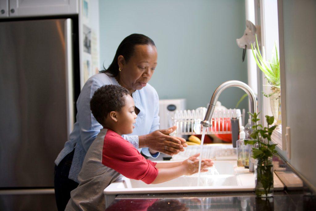 Parent teaching youth to wash their hands