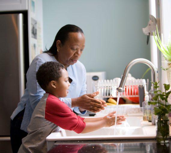 Parent teaching youth to wash their hands