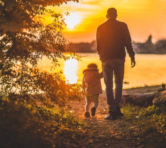 Father and daughter following pathway in sunset