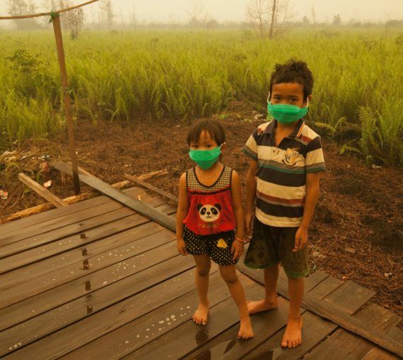 Two children in masks due to pollution from peat farms