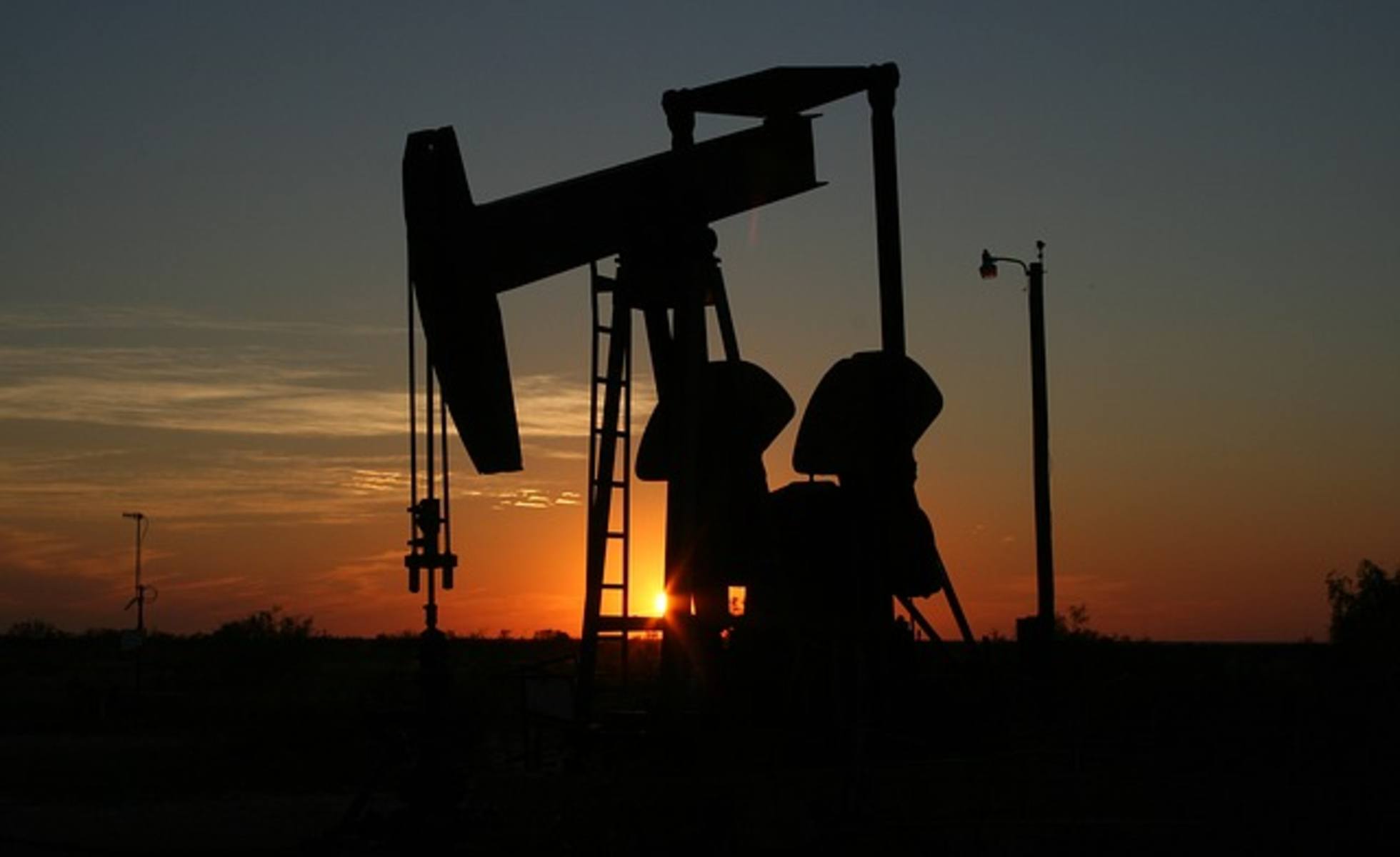 oil and gas well backlit by sunset