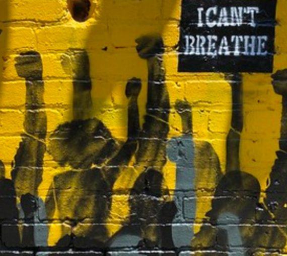 Mural of crowd with fists up holding I Can't Breathe sign against a yellow brick wall