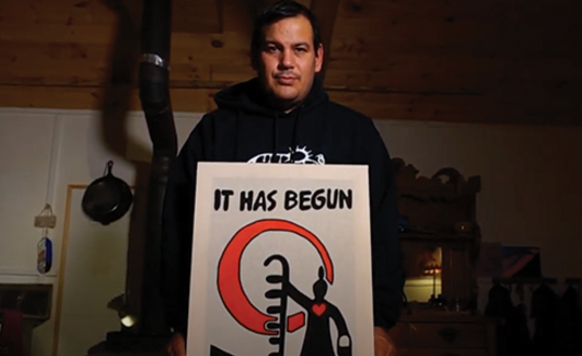 Issac Murdoch holding "It has begun" artwork.