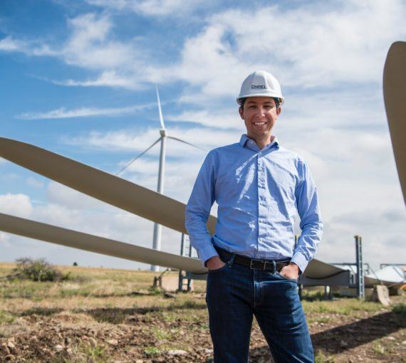 Man smiling in front of wind farm