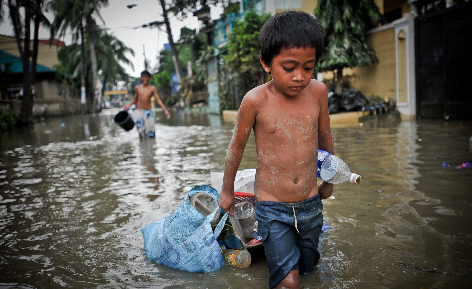 In the aftermath of Typhoon Ketsana (Ondoy), a boy drags some possessions through the flooded streets of Metro Manila.
