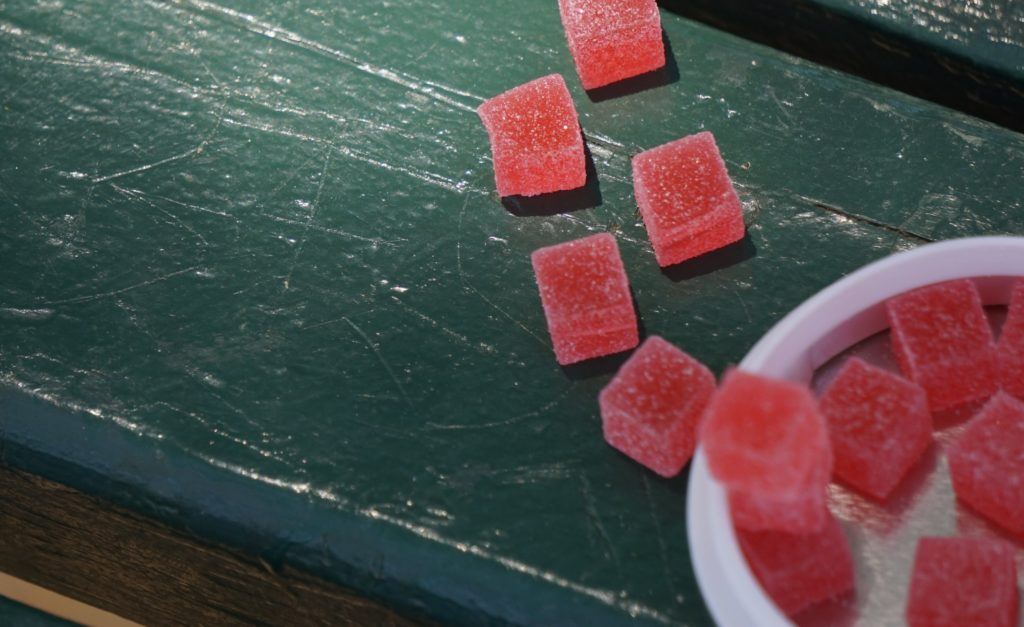 Red CBD gummies on a green, wooden table
