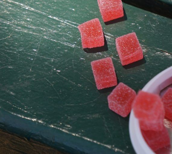 Red CBD gummies on a green, wooden table