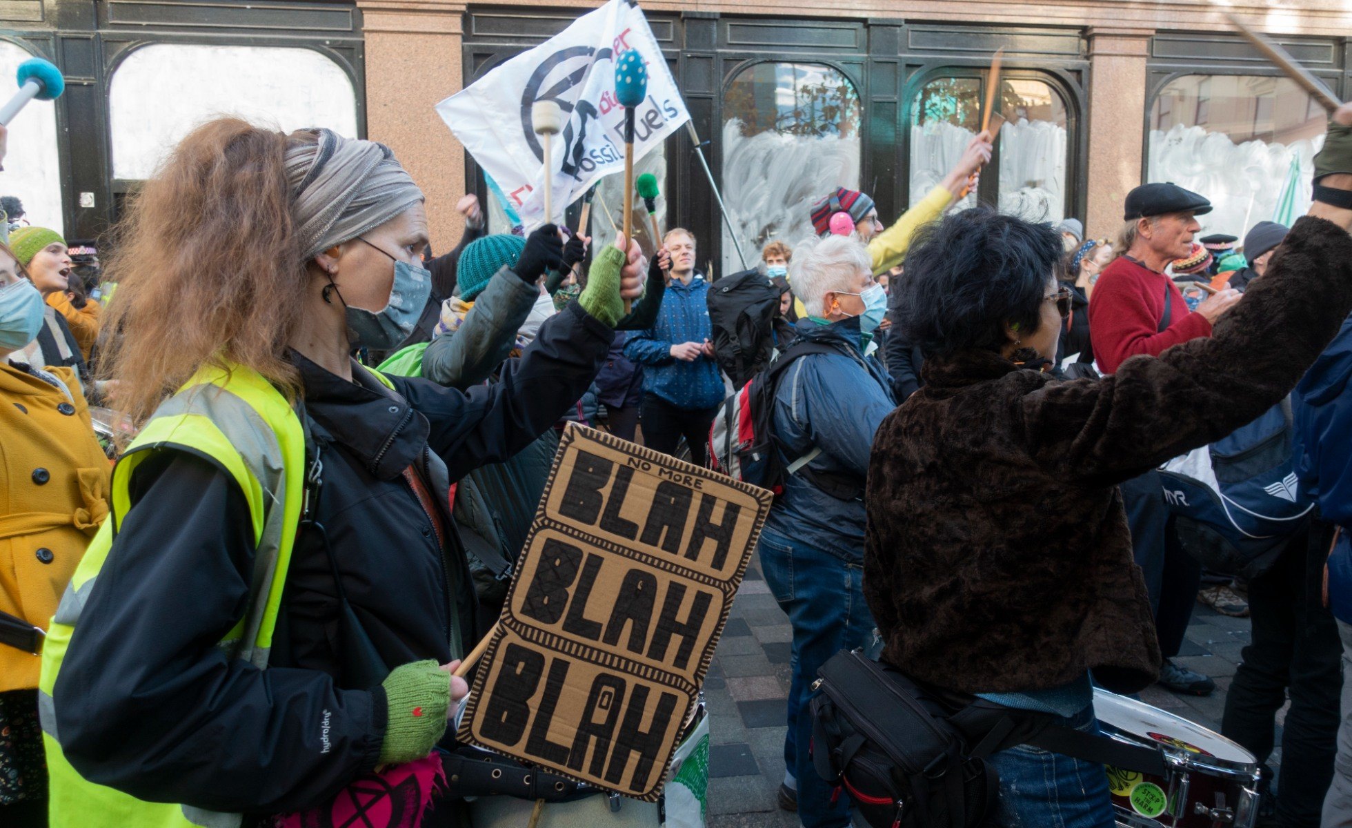 Protest outside of COP26. A women wearing a neon safety vest is holding a cardboard sign that says "Blah, blah, blah"