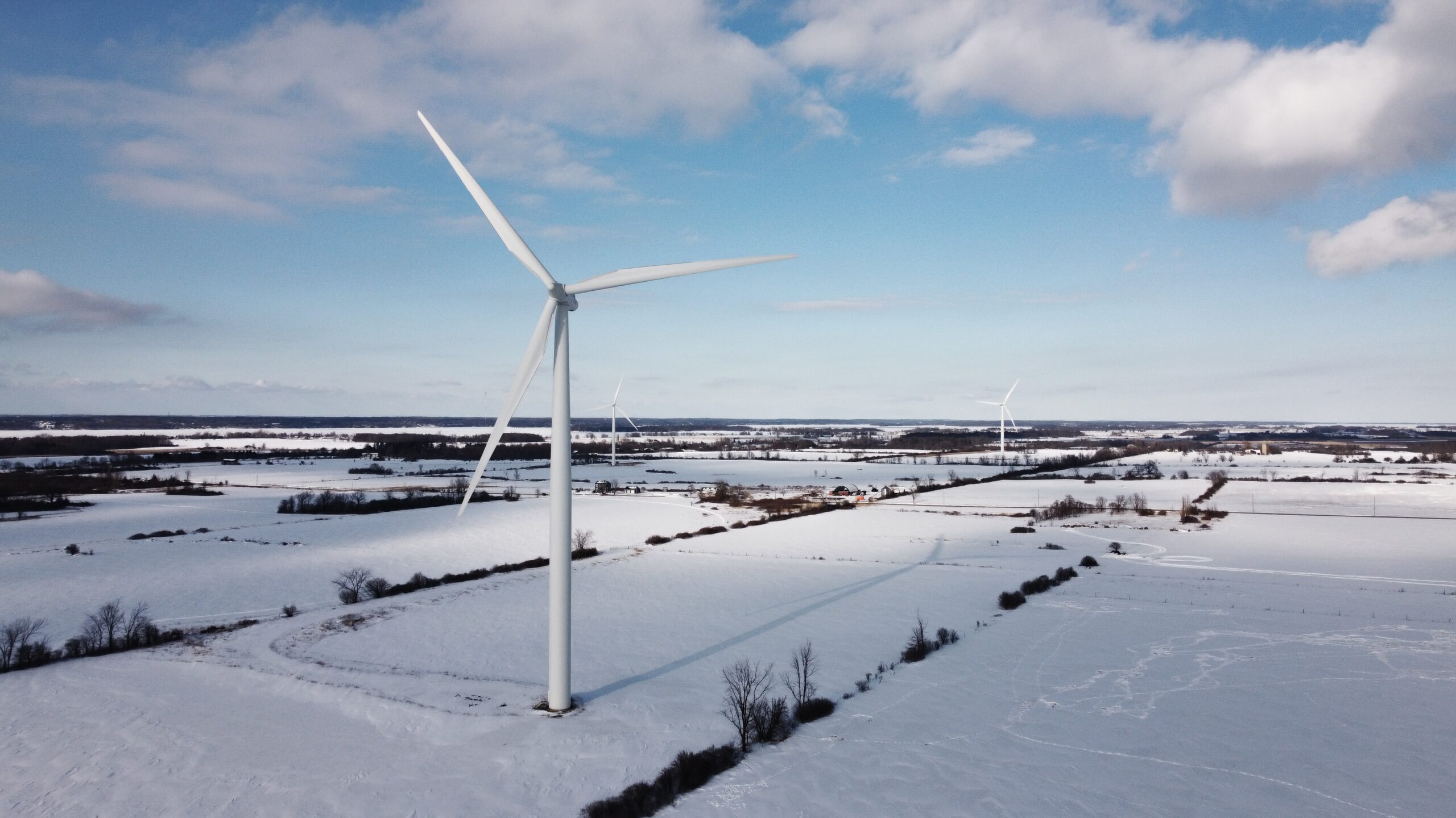 Wind turbine on snow covered ground under blue sky