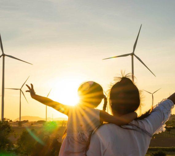 Wind turbines bright sunshine mother and daughter stretching arms to mitigate climate change