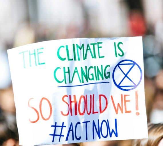 a protest activism sign saying the climate is changing so should we, act now