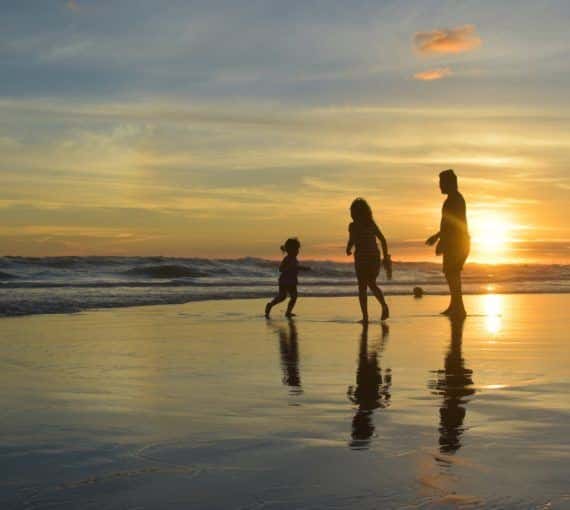 Family playing at the seashore during a sunset