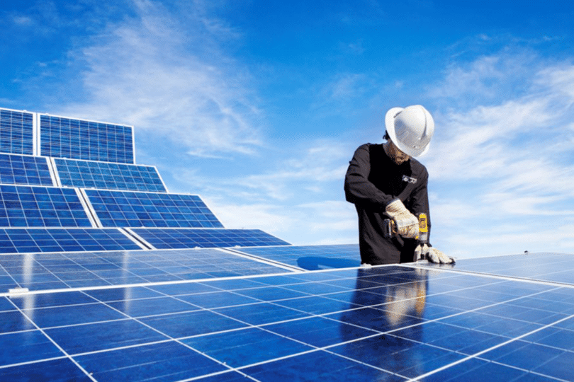 Picture of a person working on solar panels under a blue sky