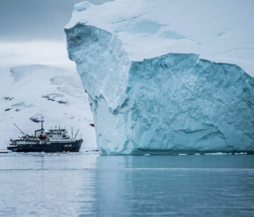 Boat beside large iceberg