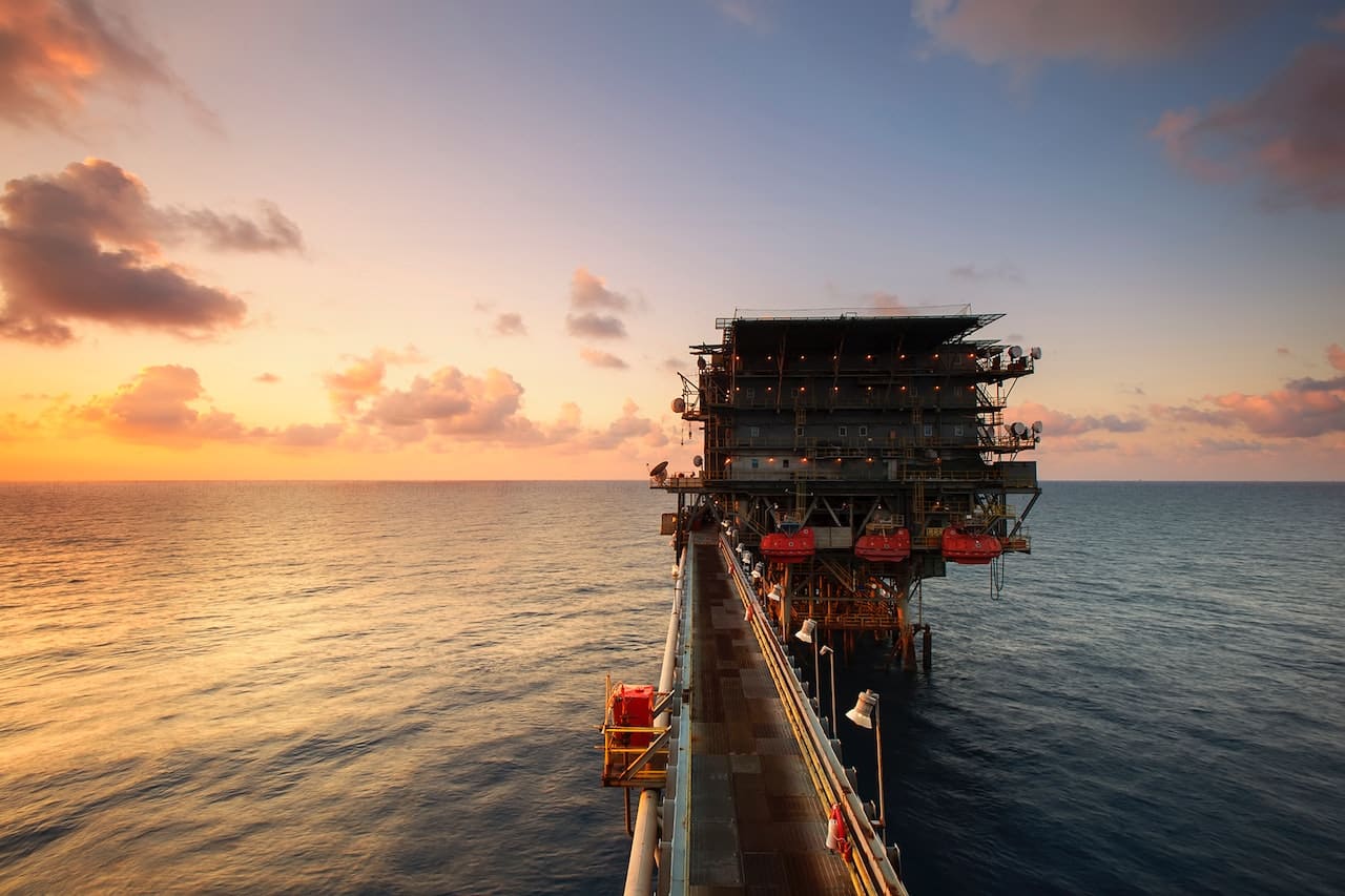 Offshore drilling rig on body of water during sunset