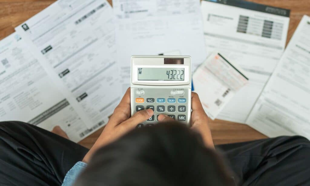 Photo of a person holding a calculator surrounded by bills