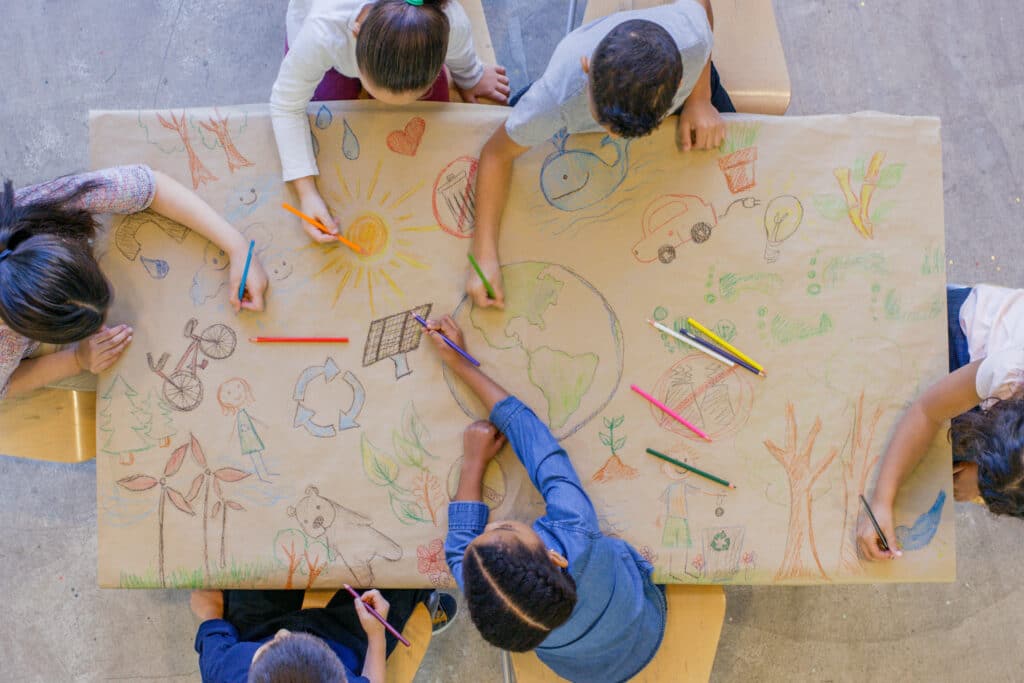 Kids at a table drawing having a green back-to-school