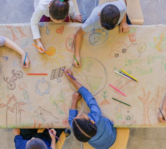 Kids at a table drawing having a green back-to-school