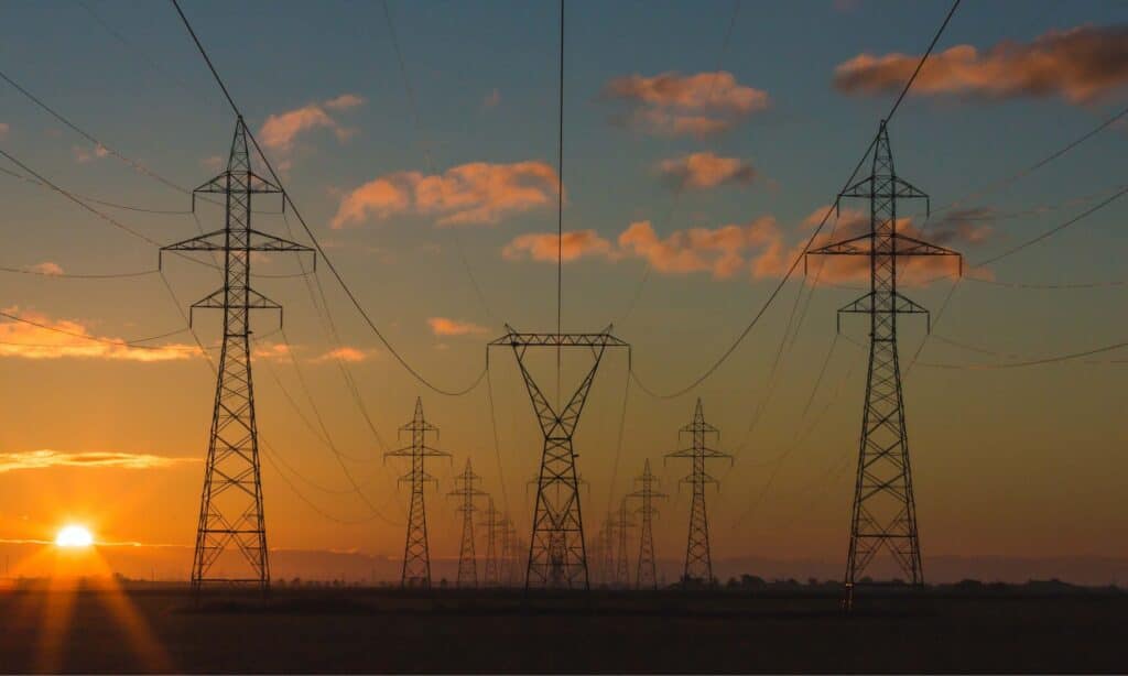 A photo of transmission lines and sunset behind pink clouds.