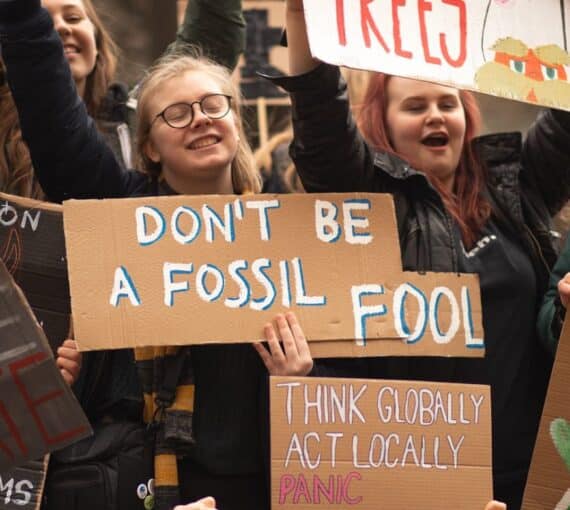 Youth holding up protest sign reading 'don't be a fossil fool'.