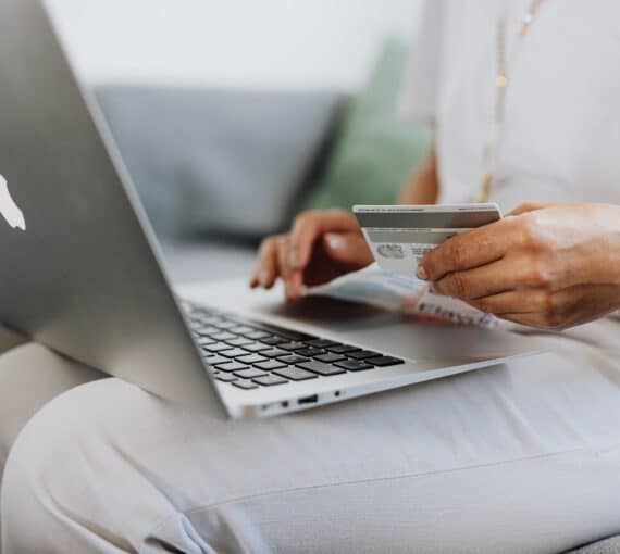 Woman sitting with her credit card out making an online purchase using her laptop.