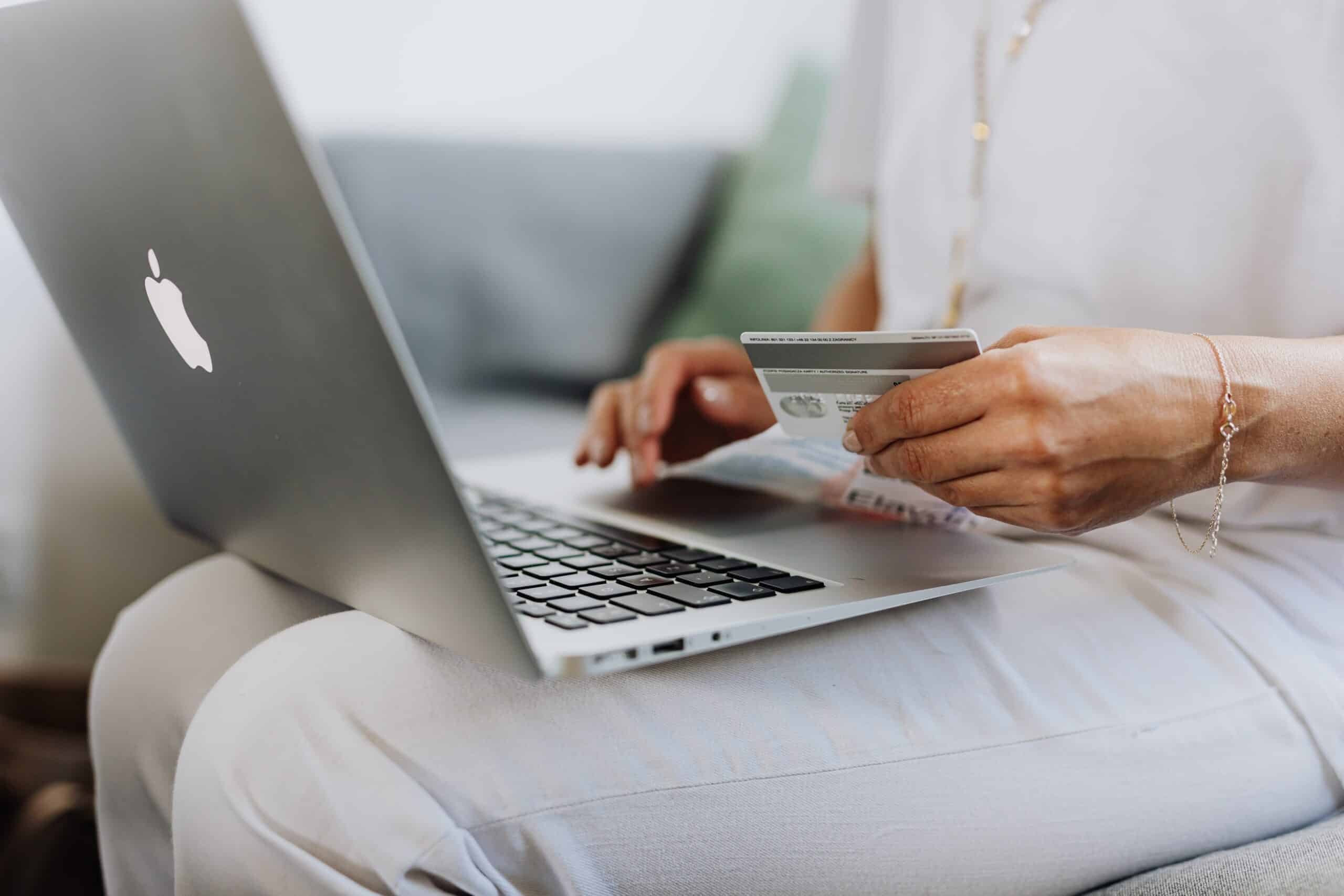 Woman sitting with her credit card out making an online purchase using her laptop.