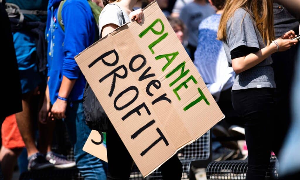 protestor holding a sign reading 'planet over profit'