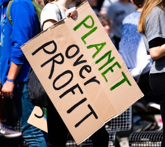 protestor holding a sign reading 'planet over profit'