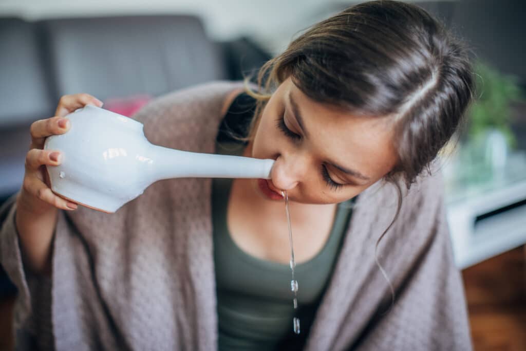 A woman using a neti pot to clear her sinuses.