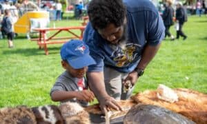 Julius Lindsay with his son, Julius III at a community event looking at animal hides