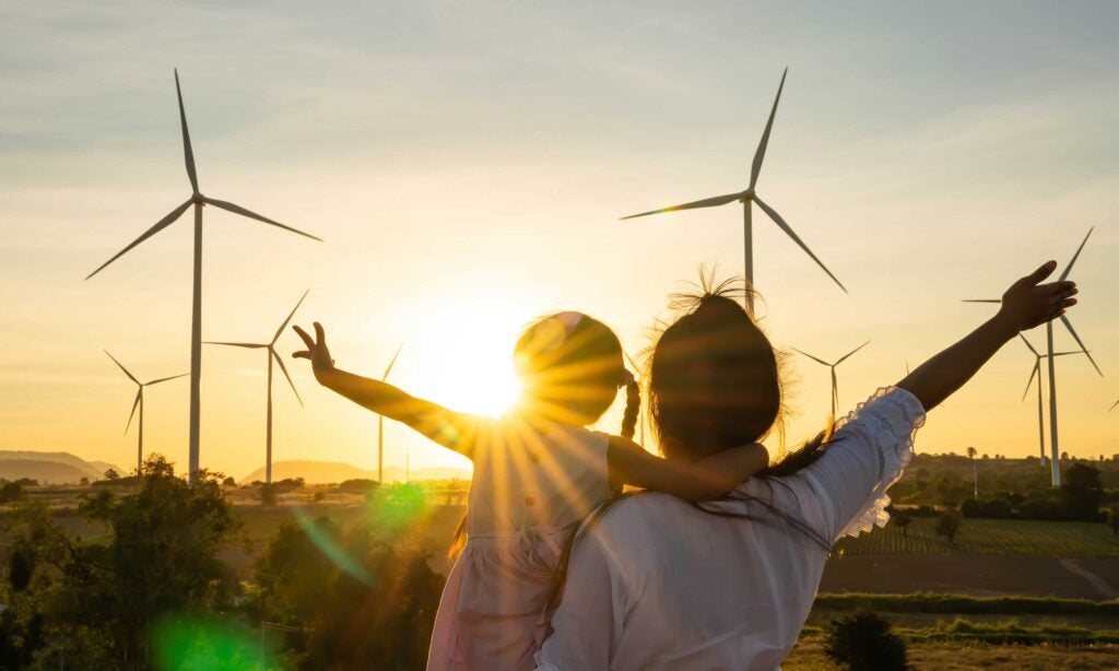 The sun rises behind a wind farm