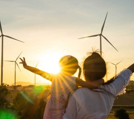 The sun rises behind a wind farm