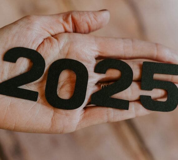 A hand holding the number '2025'