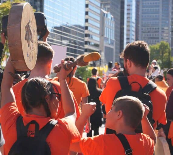 People at an 'Every Child Matters' march banging a drum, 2025