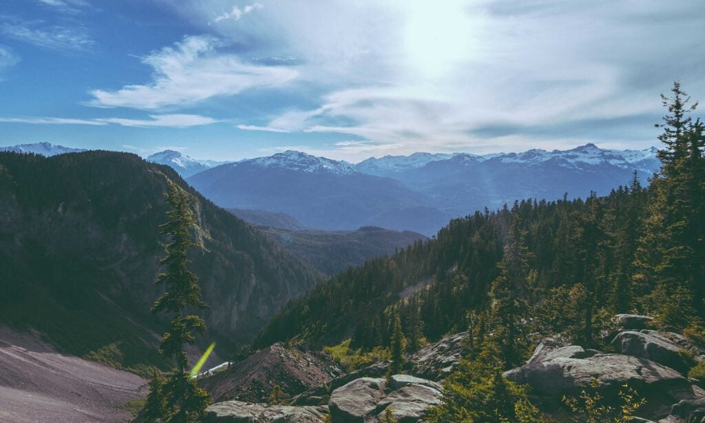 a view of a mountain range with trees and mountains in the background