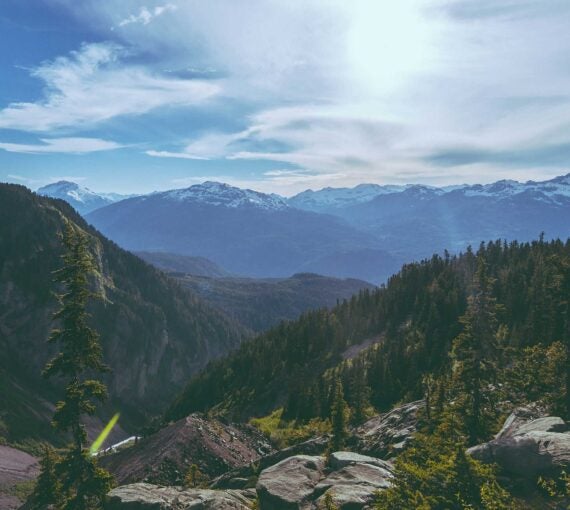 a view of a mountain range with trees and mountains in the background